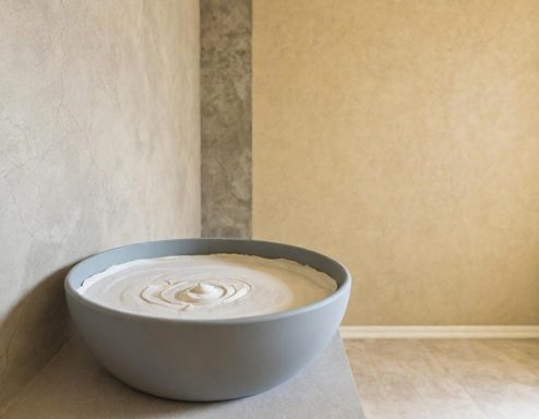 Eine große, runde Schüssel mit einer cremigen, hellen Masse auf einer neutralen Wand.